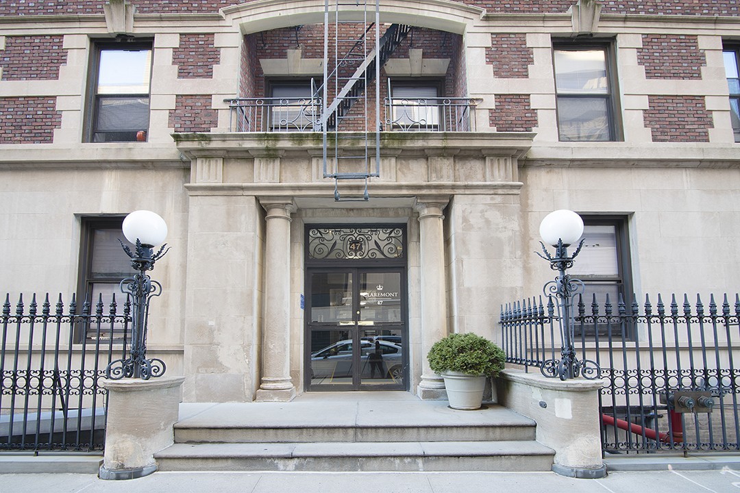 The entrance of 47 Claremont with two cement columns on either side of the door and a brick facade beginning on the second floor.