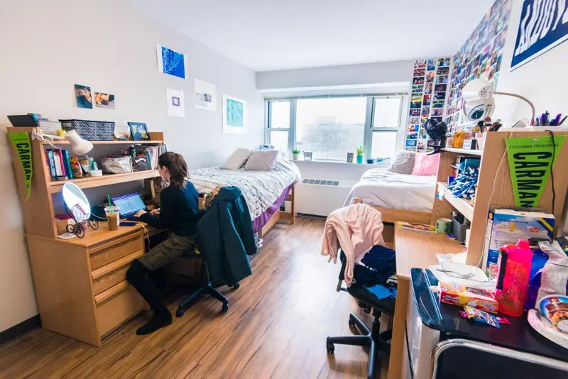 Students sitting in their dorm room inside Carman Hall that is filled with decorations.