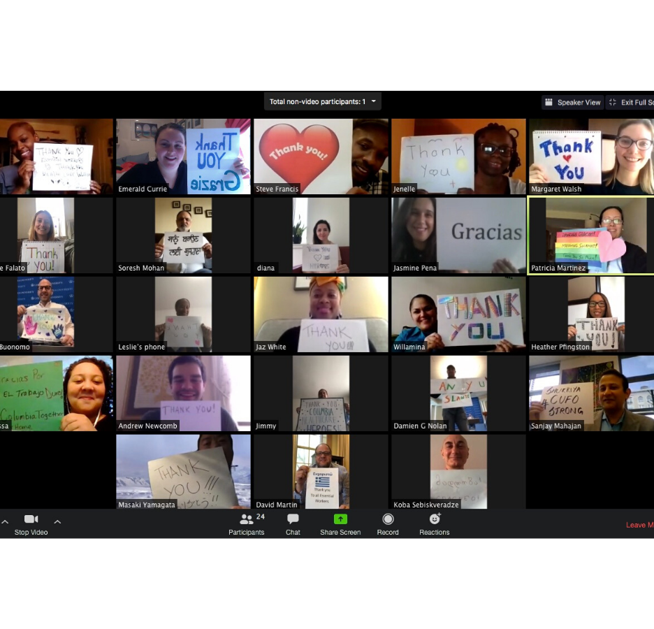 A screenshot of a video conference call showing people holding handmade thank you signs
