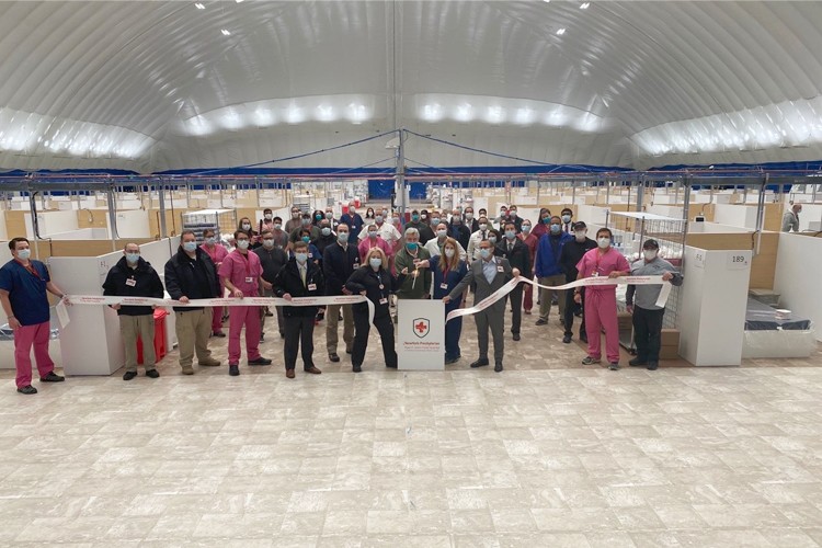 A group of people gather together to cut a ribbon inside the field hospital in the Bubble at Baker.