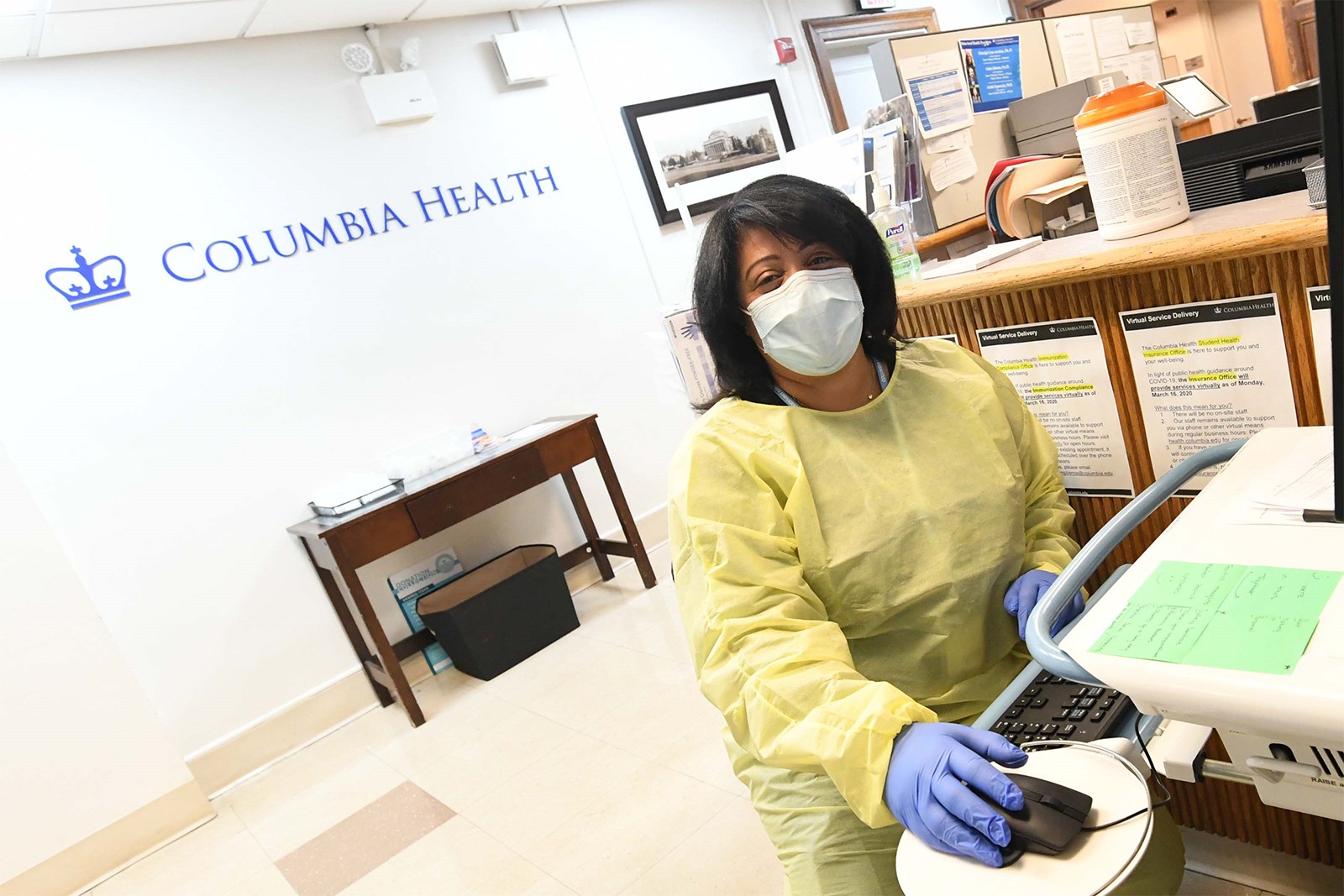 A Columbia Health employee sits at a computer in the lobby of the Health Services office.