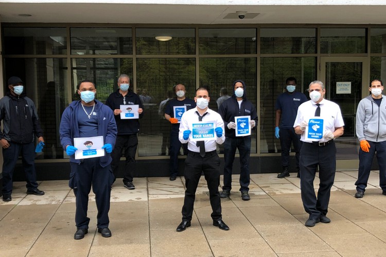 A group of Columbia Residential employees stand outside of a building entrance that is covered with windows.