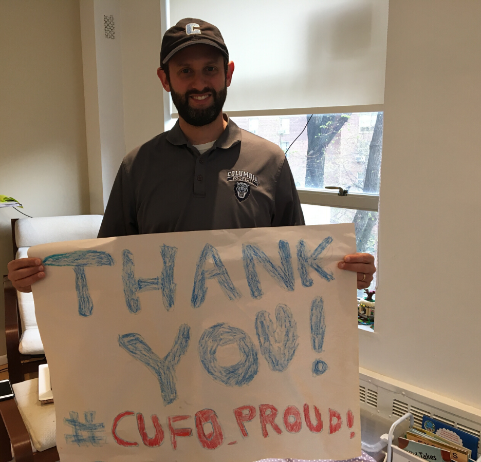 A man wearing a Columbia baseball cap holds a poster that says, "Thank you! #CUFO Proud"