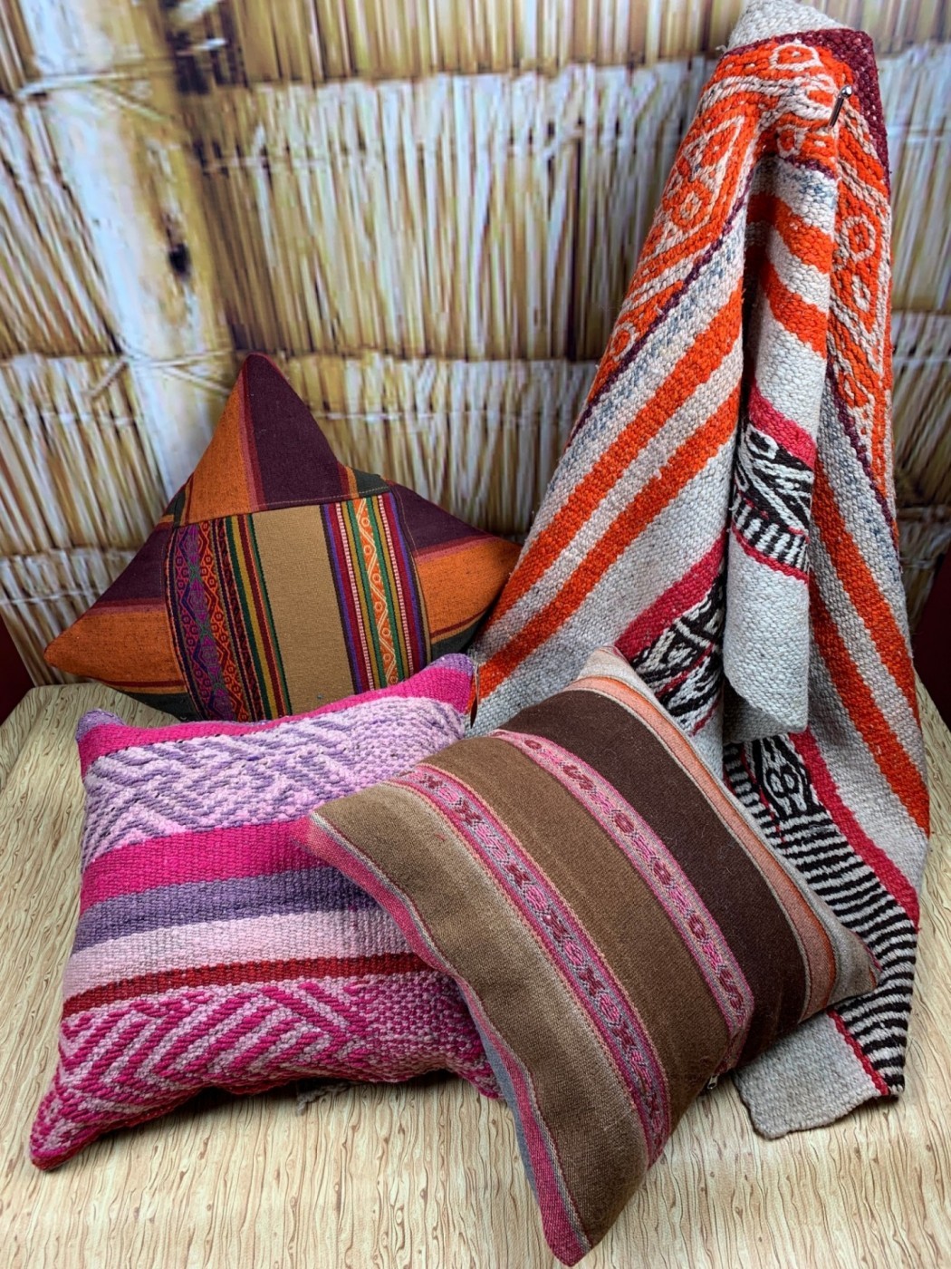 Woven pillows and a blanket on a straw ottoman.  