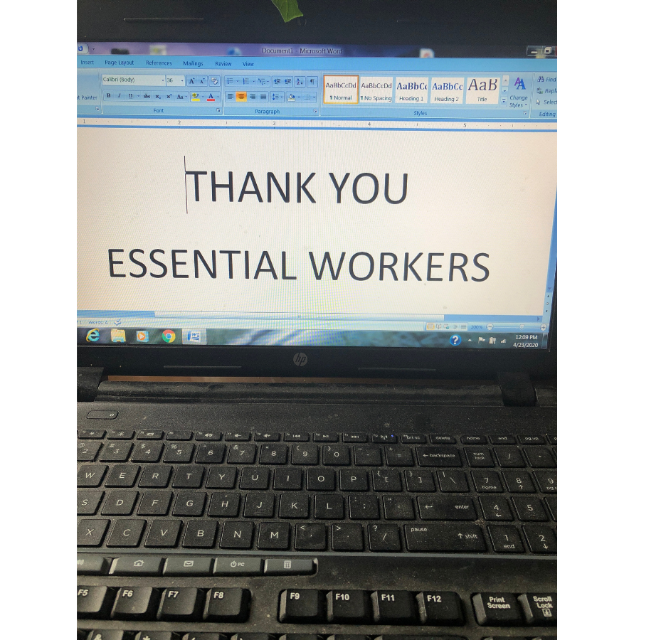 A laptop is open with a Word document on the screen that reads, "Thank you essential workers" in caps.