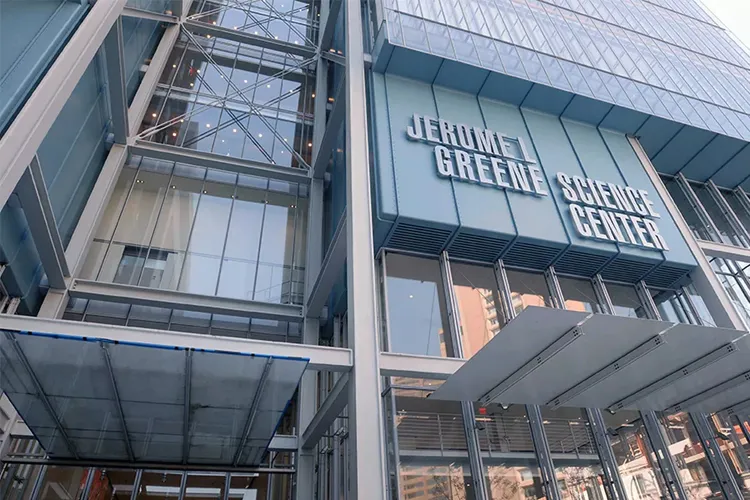 The light blue and glass facade of the Jerome L. Greene Science Center with the building name in white lettering.