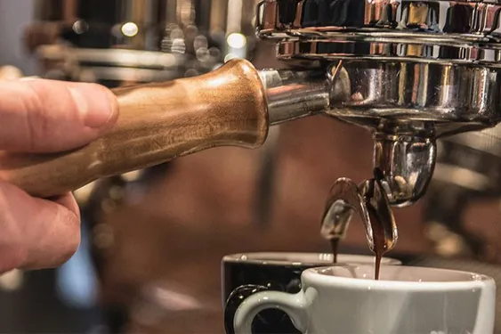 A closeup of a person making an espresso using an espresso machine.