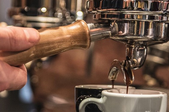 A closeup of a person making an espresso using an espresso machine.