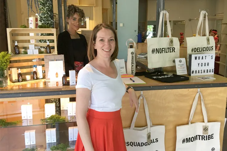 Two vendors by their tables selling hashtag tote bags and beauty products