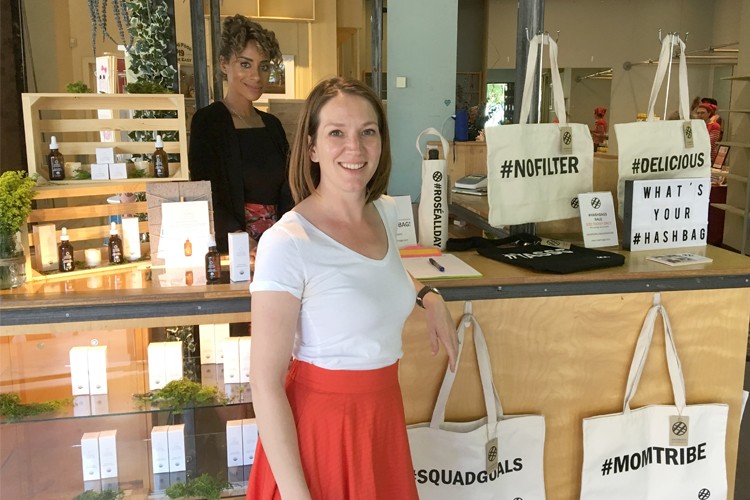 Two vendors by their tables selling hashtag tote bags and beauty products